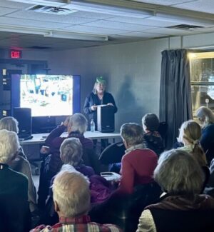 March 17. Karen Wand presents on St. Lawrence Boatbuilders. A woman presenting with a screen presentation on St. Lawrence boatbuilders