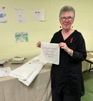Jody holding a contribution towards The Hanky Project, commemorating "Les fiiles du roi" Woman holding an embroidered contribution to The Hanky Project